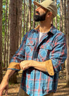 Side view of a man wearing a blue plaid flannel shirt for men adjusting the cuffs