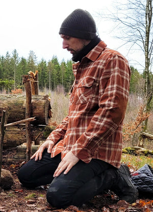 Side view of a man wearing a rust red men's cozy rugged ridge outdoor flannel shirt kneeling on the ground-XR1111RR-S,XR1111RR-M,XR1111RR-L,XR1111RR-XL,XR1111RR-XXL,XR1111RR-3XL