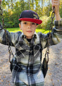 A little boy wearing a black-and-white plaid fleece jacket is swinging on a swing