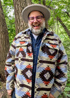 Front view of a man wearing a Coffee and Blue men's Aztec shirt jacket, hands in pockets, smiling warmly and laughing