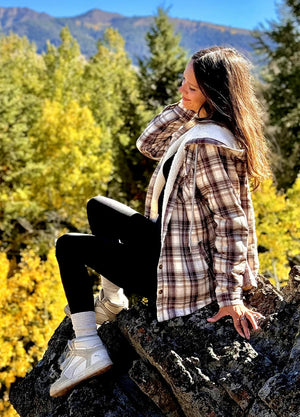 Side view of a woman wearing a chocolate sherpa-lined hooded jacket