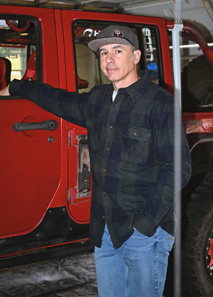 Side view of a man in a ink green men's stalwart cotton flannel shirt standing next to his car