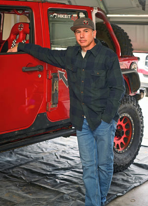 Front view of a man wearing a dark green men's stalwart cotton flannel shirt standing next to his car
