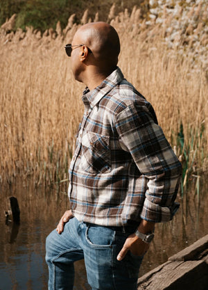 Side view of a man in a coffee white men's stalwart heavyweight cotton plaid shirt with one hand in the pocket