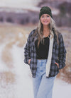 Women in a black plaid button down flannel shirt jacket with sherpa lining