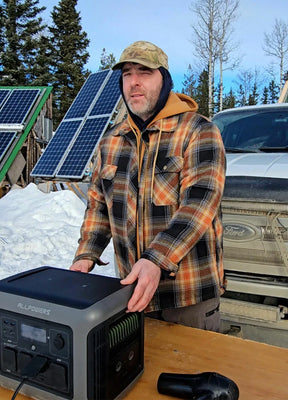 Front view of a man in a brown black men's quilted lined brushed flannel hooded jacket standing behind a desk