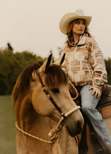 Front view of a woman on horseback wearing a zip-up khaki brown Aztec cropped jacket
