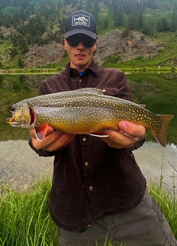 A man wearing the  Corduroy Flannel-Lined Shirt Jacket proudly holding his fresh catch.