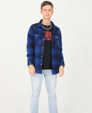 A boy wearing a navy/black buffalo plaid shirt jacket